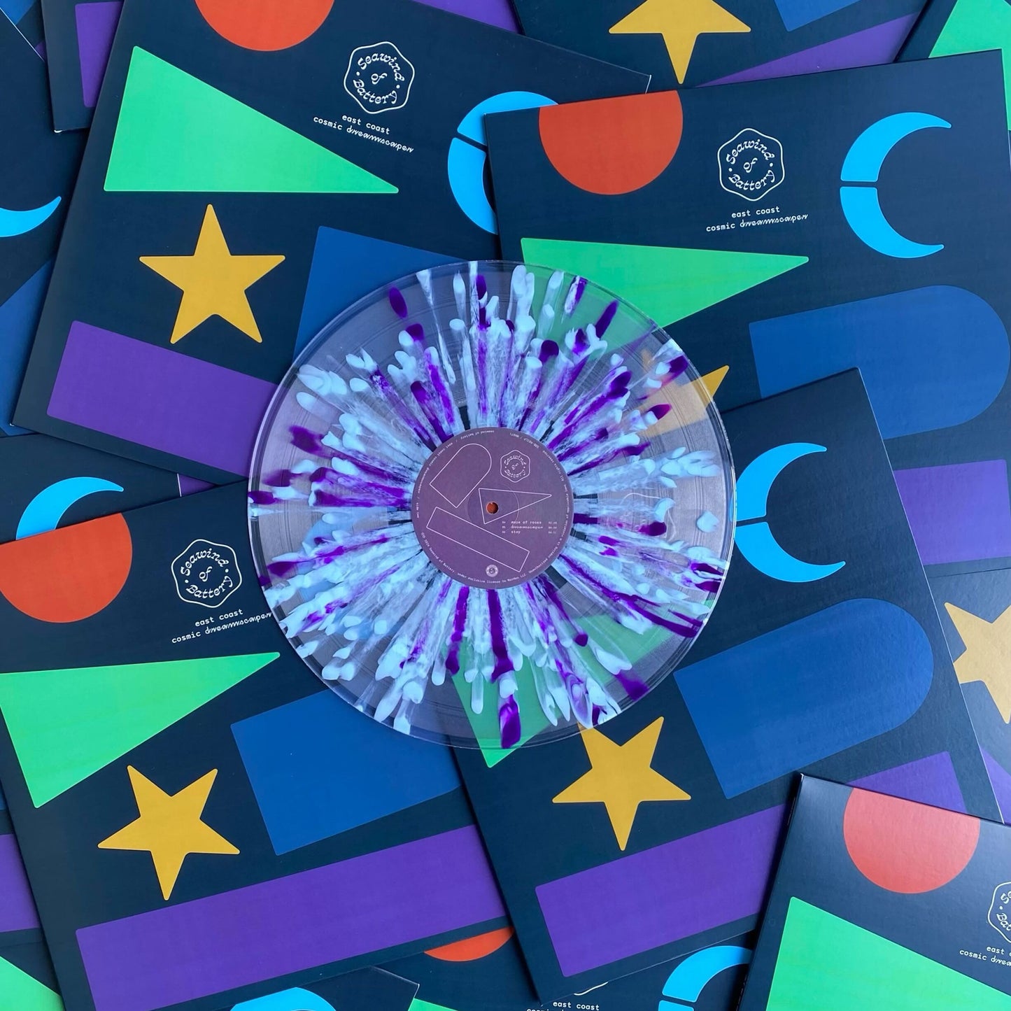 Vinyl record with a colorful design on a bed of colorful cardstock with geometric shapes and text.