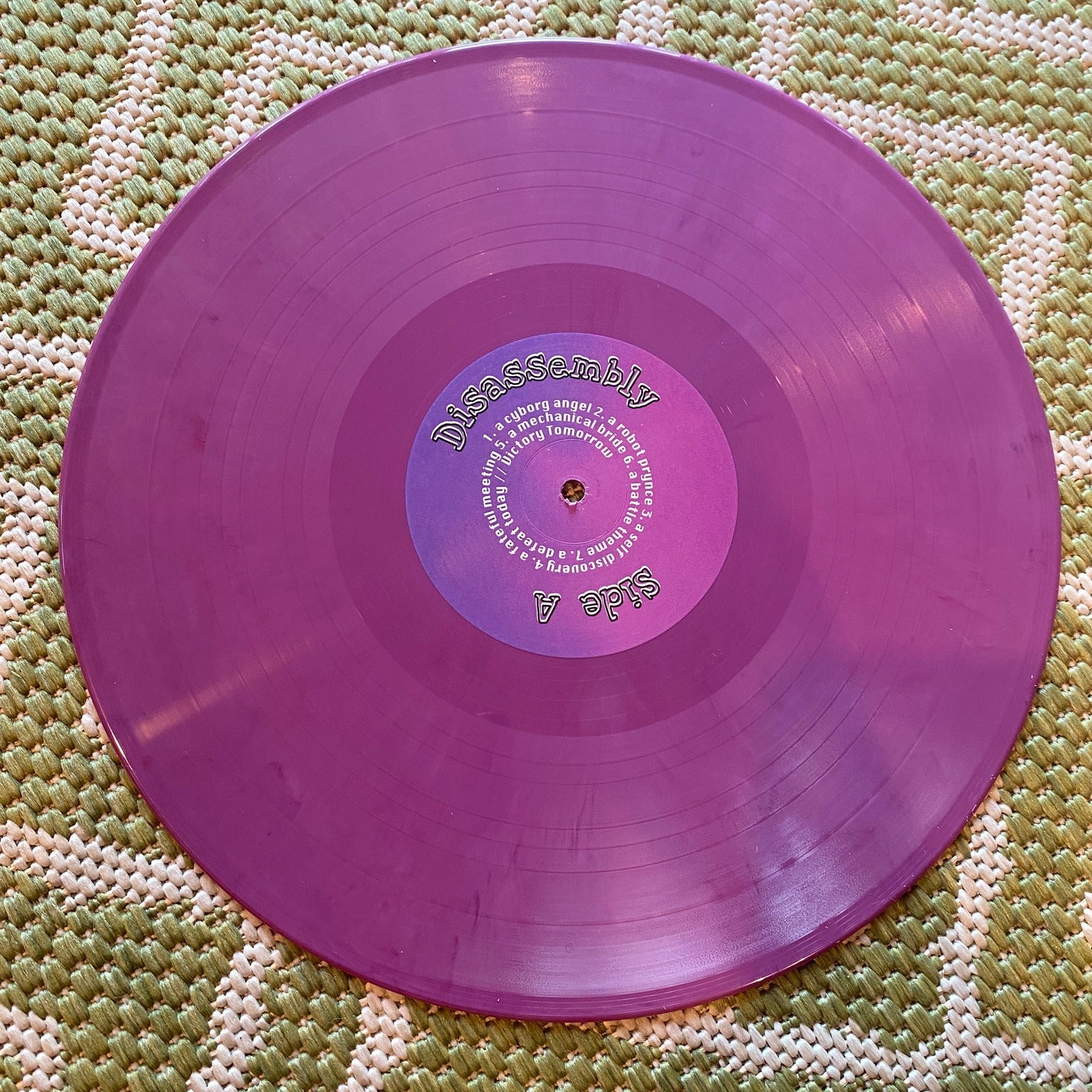 Purple vinyl record on a textured green surface