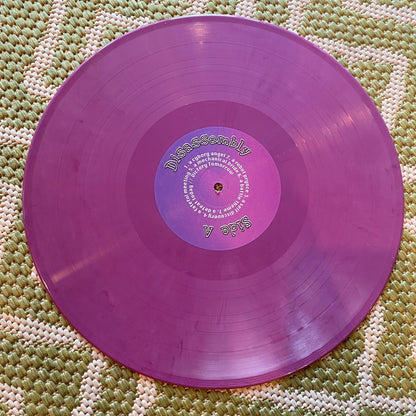 Purple vinyl record on a textured green surface
