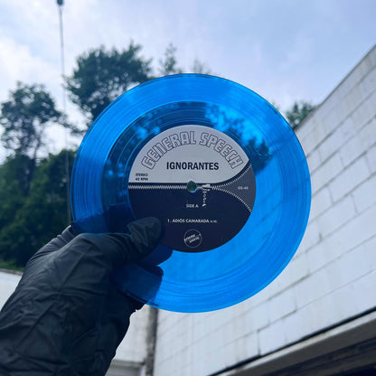 Clear/transparent blue vinyl record held by a person with a building and trees in the background