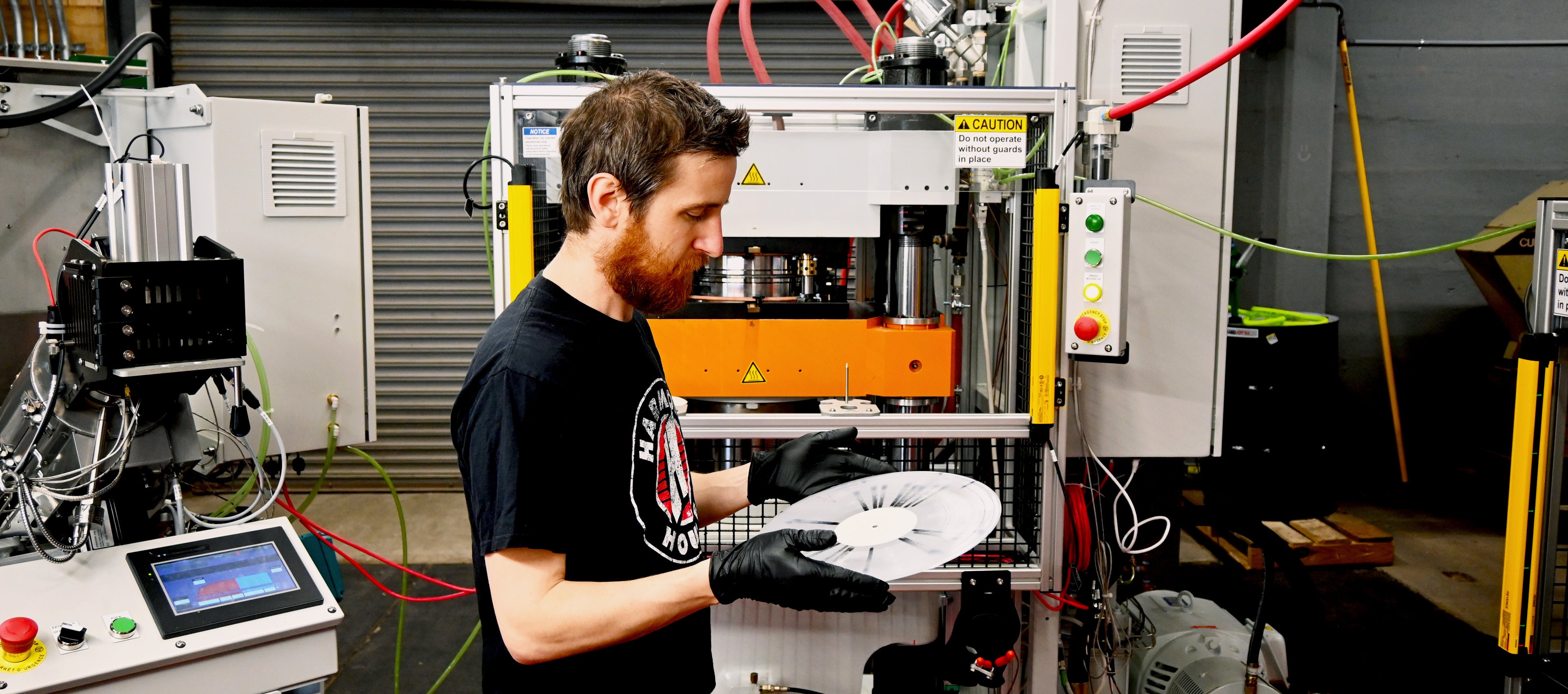 Vinyl pressing in action! Lead press operator Nick Landstrom inspects a 12" custom vinyl record at Hellbender Vinyl in Pittsburgh, Pennsylvania in front of a Viryl Technologies LiteTone machine.