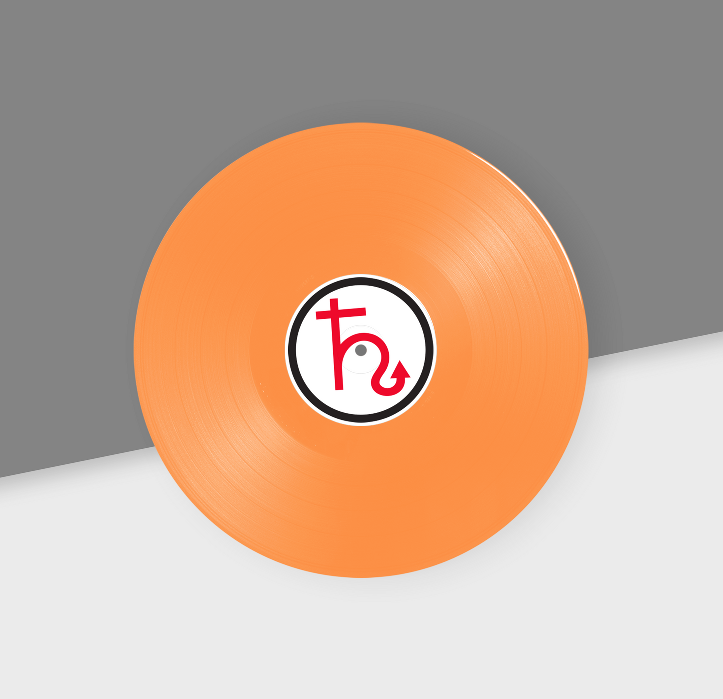 An orange 12-inch vinyl record with a black and white label in the center, placed on a gray and white background.