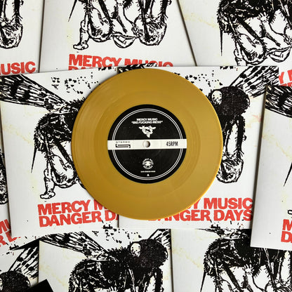 Gold vinyl record with a black label on top of 'Mercy Music' album covers.