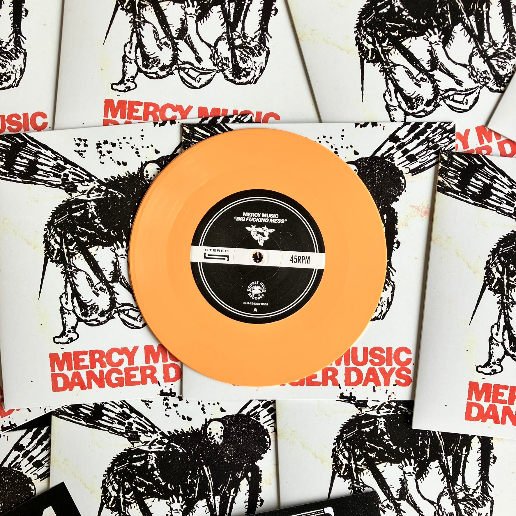 Vinyl record with peach-colored disc and black label on Mercy Music album covers.