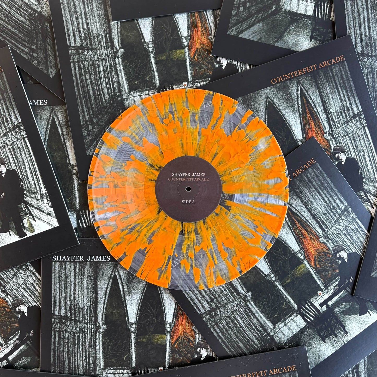 Orange and clear splatter vinyl record with 'Shayfer James' on a background of album covers